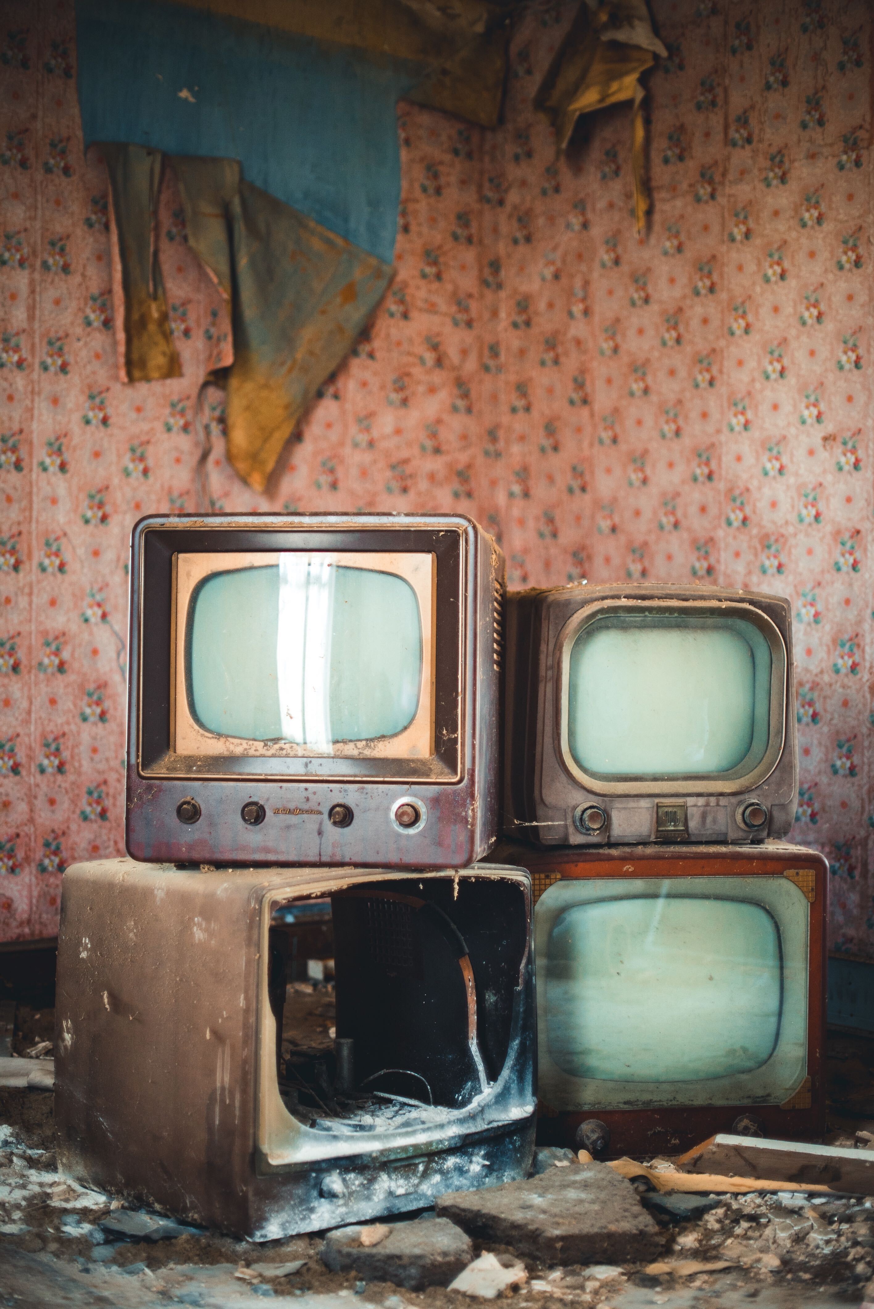 Vintage destroyed TVs with distressed wallpaper in background